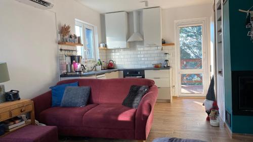 a living room with a red couch and a kitchen at Całoroczny dom na Suwalszczyźnie in Radziucie
