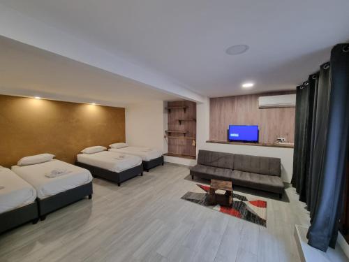a room with two beds and a couch and a tv at G3 Gamboa Beach Houses in Peniche