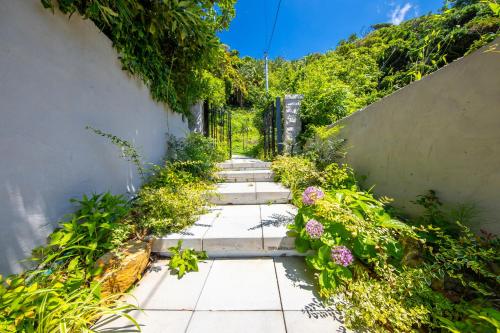 a garden path with stairs and flowers at 【南房テラス】180度パノラマオーシャンビュー絶景を楽しむリゾート別荘の家 in Kanaya