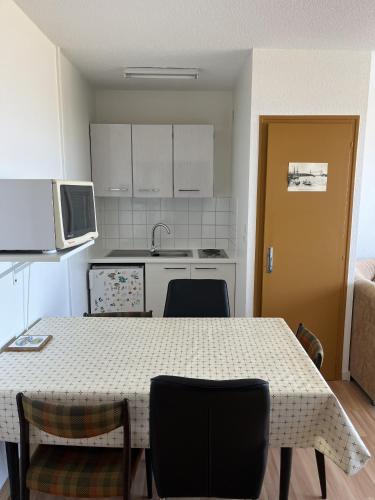 une cuisine avec une table et des chaises et une cuisine avec des armoires blanches dans l'établissement Le Voilier bleu, à Saint-Jean-de-Monts