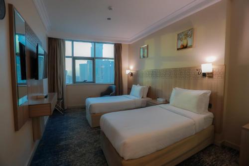 a hotel room with two beds and a window at Nawazi Towers Hotel in Makkah