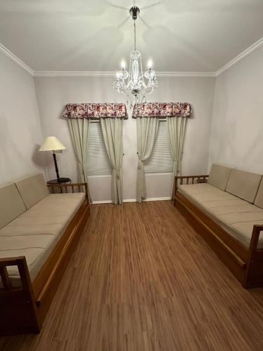 a living room with two beds and a chandelier at Center Suiço Flats in Campos do Jordão