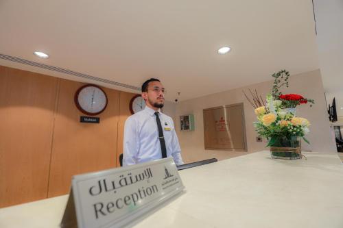 a man standing in a room with a reception desk at Nawazi Towers Hotel in Makkah