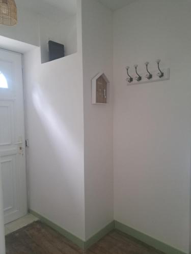 a room with a white wall with hangers on it at La Mancelliere in Isigny-le-Buat