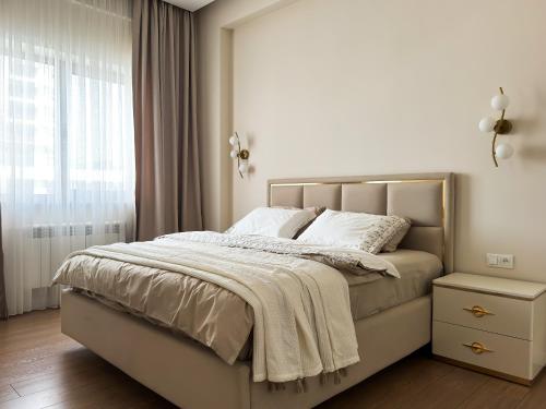 a white bedroom with a bed with a window at Family Suite for 4 - 6 people! Direct access to Tashkent CITY MALL, Central Park, Hilton Hotel, Chorsu Bazaar! in Tashkent
