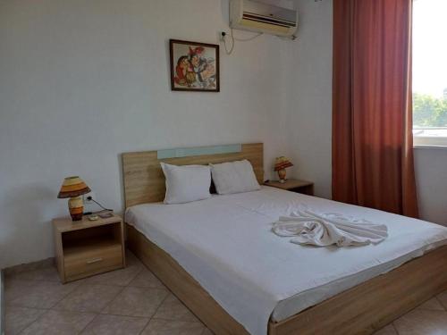 a bedroom with a large bed with white sheets and a window at Крин in Sinemorets