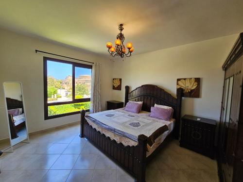 a bedroom with a bed and a window and a chandelier at Twinhouse for rent in Marassi in El Alamein