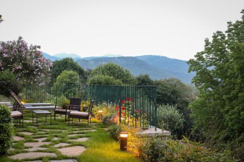 a garden with benches and flowers with mountains in the background at La Valletta Relais in Bergamo