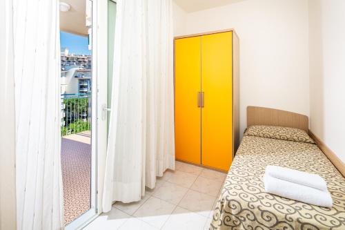 a bedroom with a bed and a yellow door at Appartamenti BIANCO NERO in Lignano Sabbiadoro