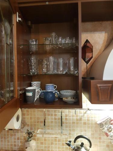 a kitchen cabinet with glasses and dishes on it at HoneyHouse in Kádhion