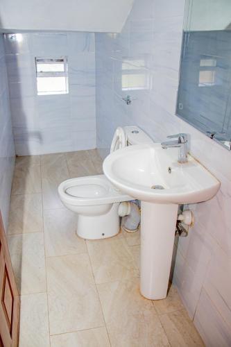 a white bathroom with a toilet and a sink at Kathy's Serene Suites in Nairobi
