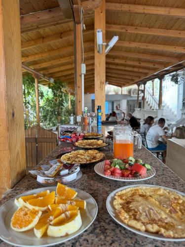 a table with plates of food and fruit on it at Garden Villa Veli in Ksamil