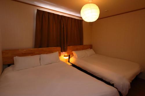 two beds in a room with a window and a lamp at Rose Garden in Asahikawa