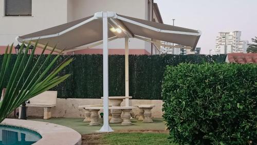 a white umbrella over a picnic table next to a pool at Kame House in Gandía