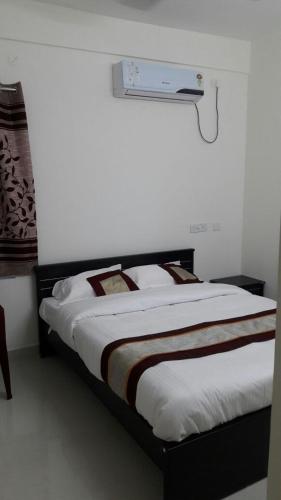 a bed in a room with a white wall at 7 Hills Service Apartments in Chennai