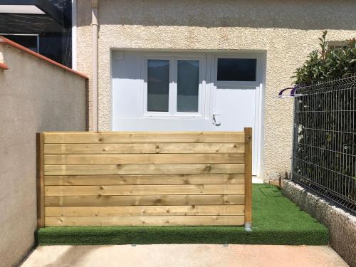 une clôture en bois devant une maison avec une porte dans l'établissement Studio indépendant 17m2, à Argelès-sur-Mer