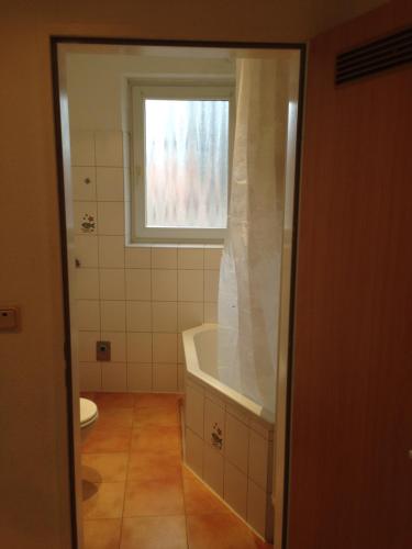 a bathroom with a bath tub and a window at City Apart Hannover in Hannover