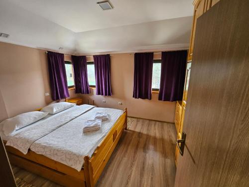 a bedroom with a large bed with purple curtains at Apartmani Trg in Zlatibor