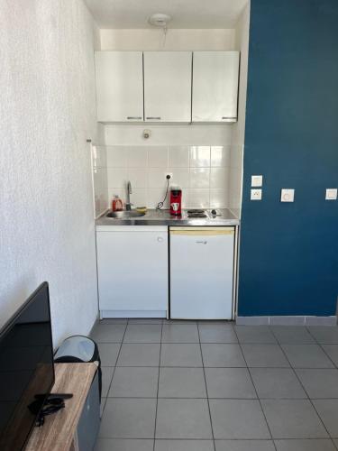 Elle comprend une petite cuisine avec des placards blancs et une porte bleue. dans l'établissement Studio centre ville, à Marseille
