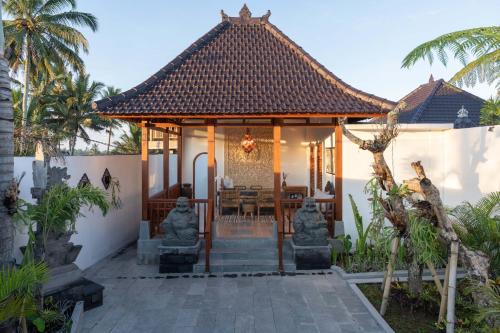 a home with a pavilion with statues in front of it at Maddu Suites in Ubud