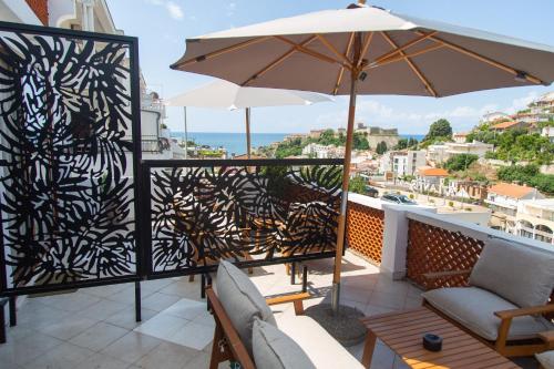 a balcony with an umbrella and chairs and a table at Apartments Milla in Ulcinj