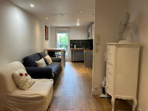 Una sala de estar con un sofá y una cocina. en Paris Eiffel Tower et Disney apartments, parkings gratuits et sécurisés, 10 minutes métro to Paris, en Nogent-sur-Marne