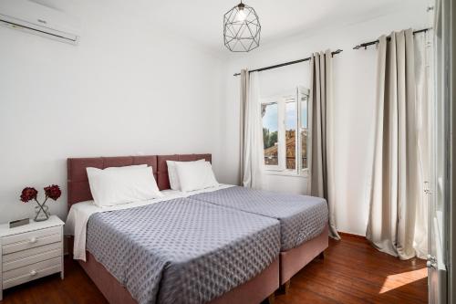 Un dormitorio blanco con una cama y una ventana. en Eveniki house, en Pelekas