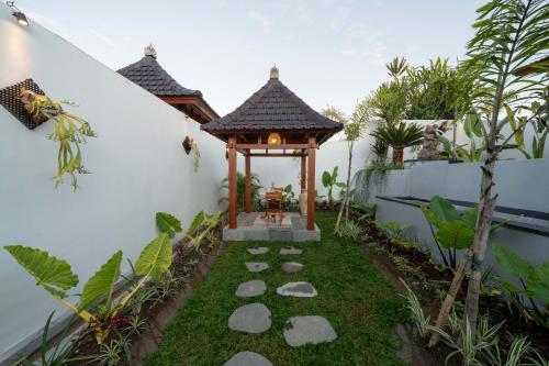 a small garden with a gazebo in a yard at Maddu Suites in Ubud