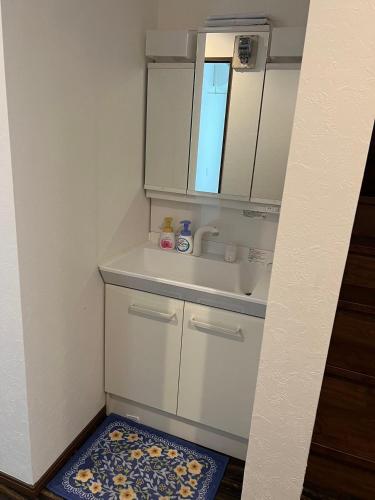 a white bathroom with a sink and a mirror at 民泊TOKYO one シェアハウス in Tokyo