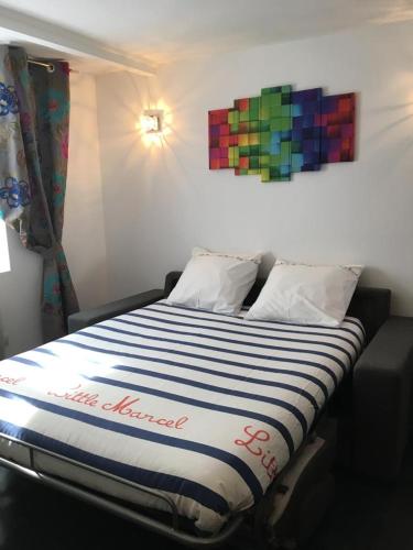 un lit dans une chambre avec un tableau coloré sur le mur dans l'établissement Studio en plein coeur de Trouville, à Trouville-sur-Mer