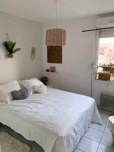 un lit blanc dans une chambre avec une fenêtre dans l'établissement GrandT3 terrasse vue sur vélodrome, à Marseille