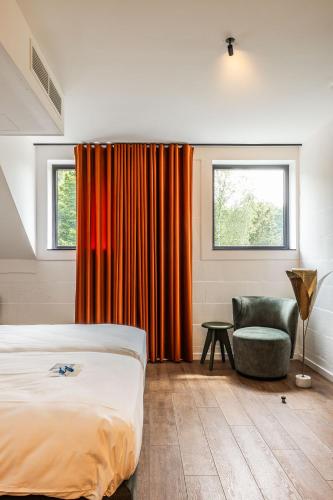 a bedroom with a bed and a chair and a window at Gare 55 in Evergem