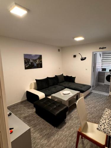a living room with a black couch and a table at Guest House deluxe in Orašje