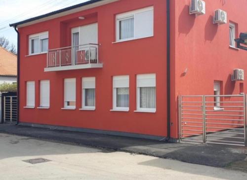 a red building with white windows and balconies at Guest House deluxe in Orašje