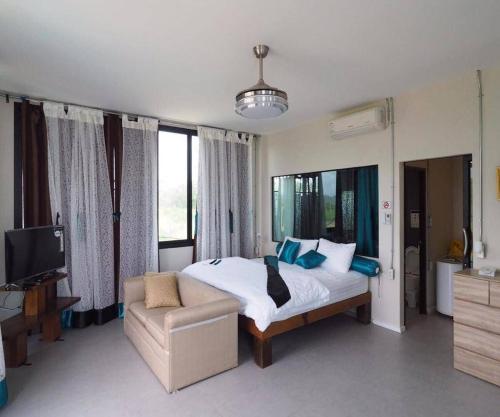 a bedroom with a bed and a couch and a tv at Daiya Nirvana Pool Villa, Khao Yai in Klang Dong