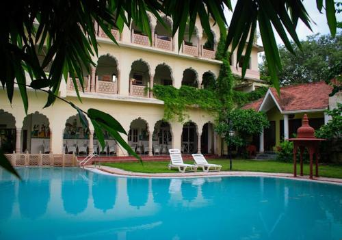a hotel with a swimming pool in front of a building at Hotel Bissau Palace in Jaipur