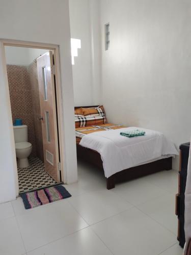 ein Schlafzimmer mit einem Bett und ein Badezimmer mit einer Toilette in der Unterkunft Harmony Resto&Homestay in Lambangkuning