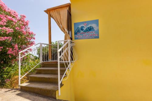 a yellow building with stairs leading up to a sign at Case vacanza Barbatoja in Fetovaia