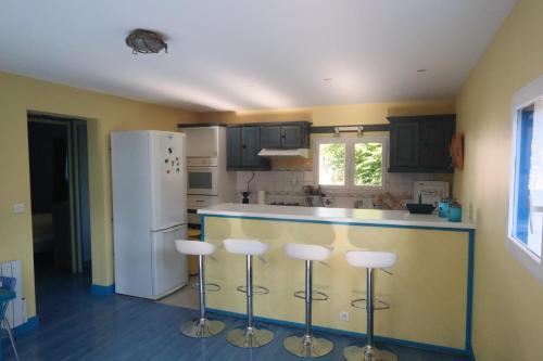 La cuisine est équipée d'un comptoir avec tabourets et d'un réfrigérateur. dans l'établissement Petite maison de vacance pour 6 personnes, quartier calme, à La Teste-de-Buch