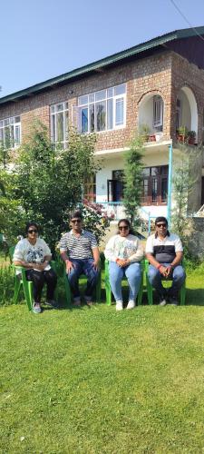 a group of men sitting in chairs in the grass at Elizabeth paying guest house Tangmarg gulmarg in Gulmarg