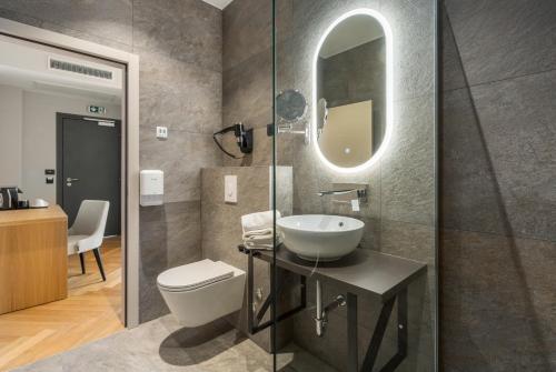 a bathroom with a sink and a toilet and a mirror at Hotel Squero in Rovinj