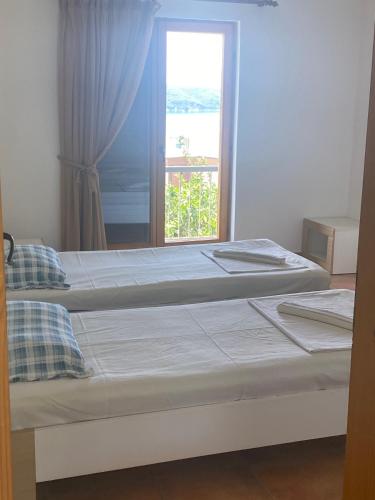 two beds in a room with a window at Green olive 1 in Pržno