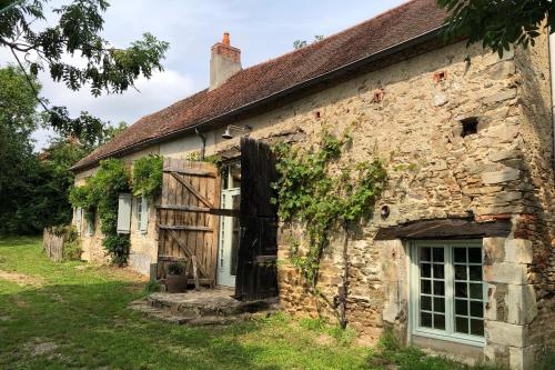 an old stone house with a door and ivy at Gîte au Bray in Bellenaves