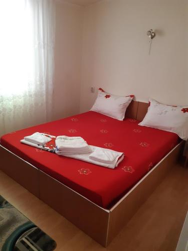 a bed with red sheets and white towels on it at CASA IZA in Băile Herculane