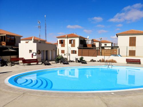 - une grande piscine dans une cour avec des maisons dans l'établissement Casa Silencio, Villa with terrace, garden and large pool area, à Corralejo