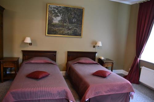 a bedroom with two beds and a picture on the wall at Birinu Pils in Bīriņi