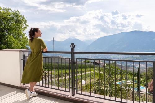 a woman standing on a balcony looking out at the mountains at Hotel Meinhardt in Schenna