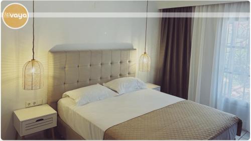 a bedroom with a large white bed with two lamps at Vaya Zorba Studios in Skiathos Town