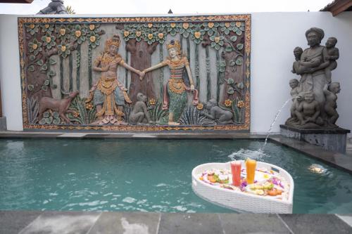 a pool with a bowl of food in front of a mural at Maddu Suites in Ubud