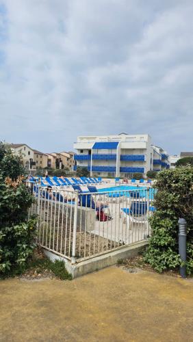 a fence with blue umbrellas in front of a building at Lacanau, Résidence Bleu Marine, appartements 2e étage, exceptionnels car balcon face et vue océan avec piscine ! Et avec parking réservé in Lacanau-Océan